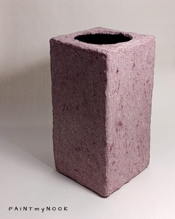 A pink colored rectangular papier mache vase
