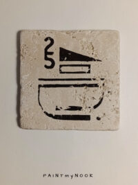 Travertine coaster with a dark brown modernist graphic printed on it