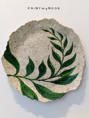 A decorative papier mache plate with a fern leaf painted in green color