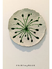 A paper mache decorative plate with green sprouts painted on it