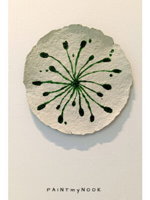 A paper mache decorative plate with green sprouts painted on it