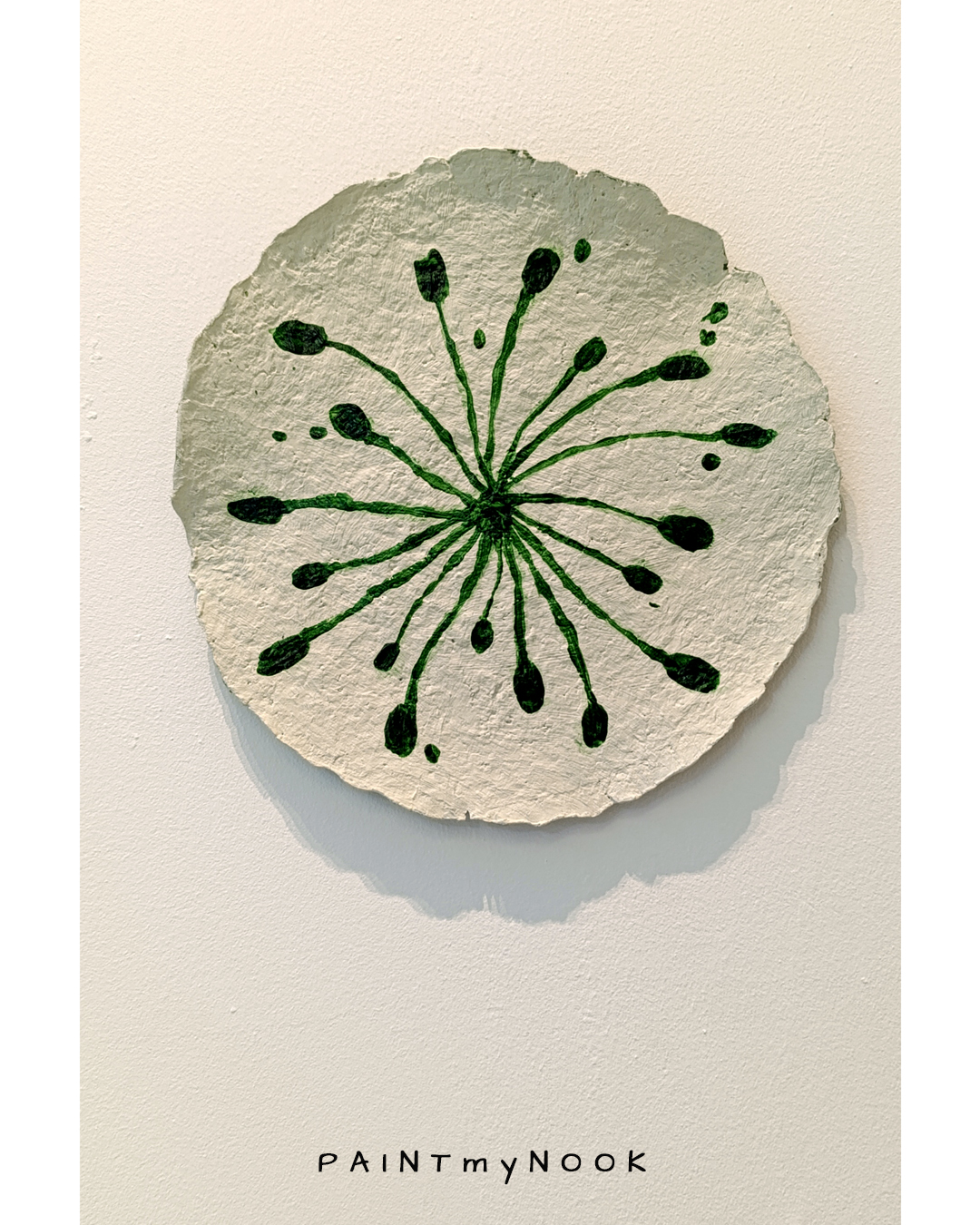 A paper mache decorative plate with green sprouts painted on it