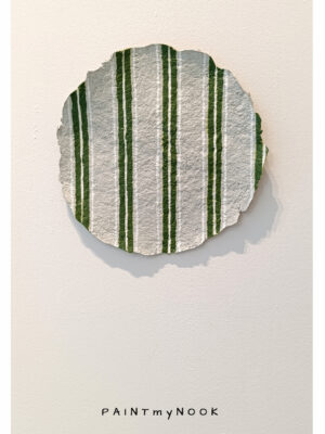 A paper mache decorative plate with green stripes painted on it