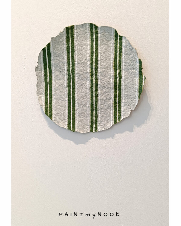 A paper mache decorative plate with green stripes painted on it