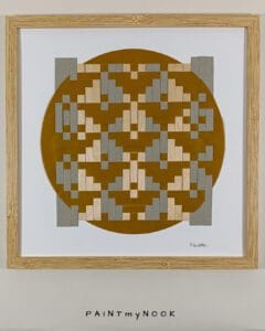 Framed wall decor featuring a yellow ochre paperweaving project