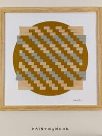 Framed wall decor featuring a yellow ochre paperweaving project