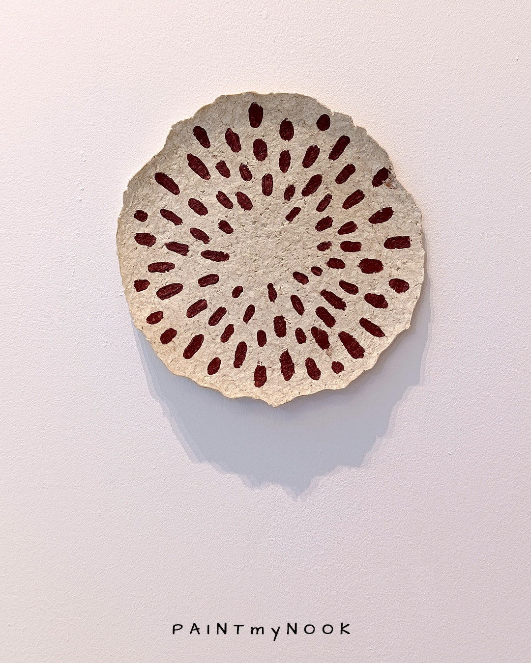 A paper mache decorative plate with red seeds painted on it