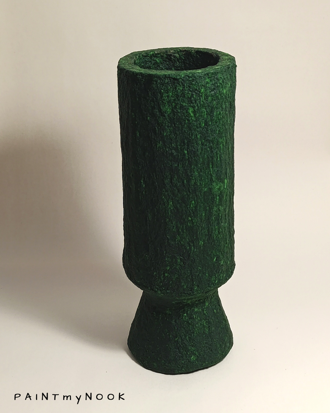 A deep green cylindrical papier mache vase with foot
