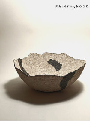A papier mache bowl with an abstract pattern in two shades, beige and dark grey