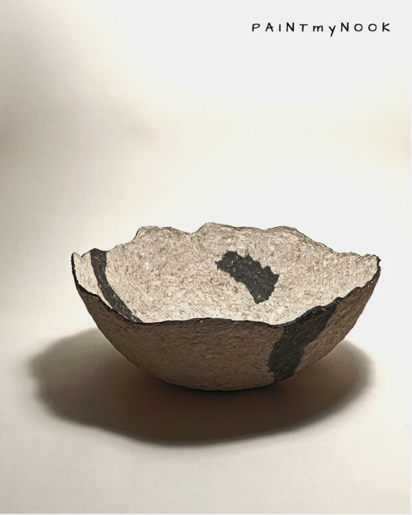 A papier mache bowl with an abstract pattern in two shades, beige and dark grey