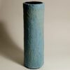 A light blue papier mache cylindrical vase