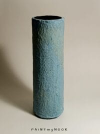 A light blue papier mache cylindrical vase