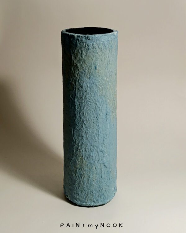 A light blue papier mache cylindrical vase
