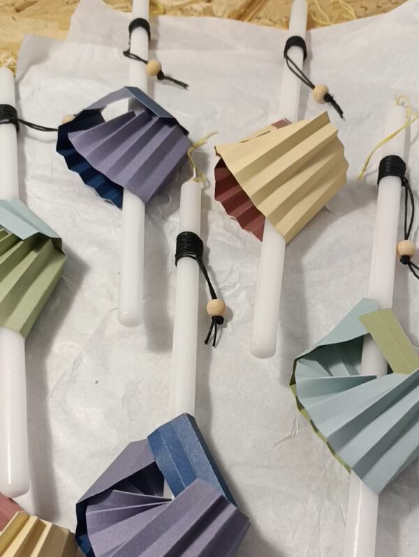 white easter candles decorated with a folded colored paper ornament and black wax thread