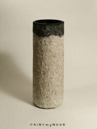 A beige and grey cylindrical papier mache vase