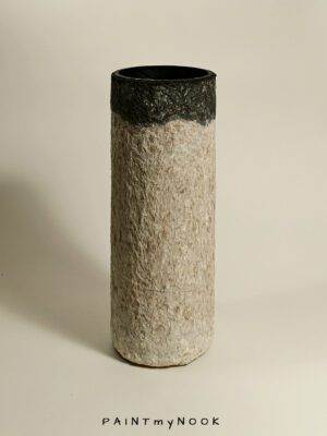 A beige and grey cylindrical papier mache vase