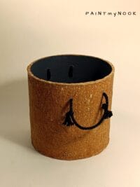 A cylindrical, orange colored papier mache planter cover