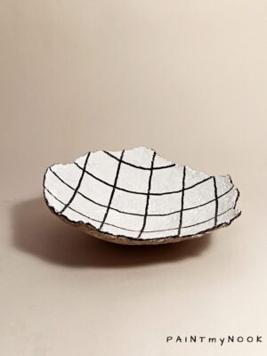 A white papier mache bowl with a grid drawing