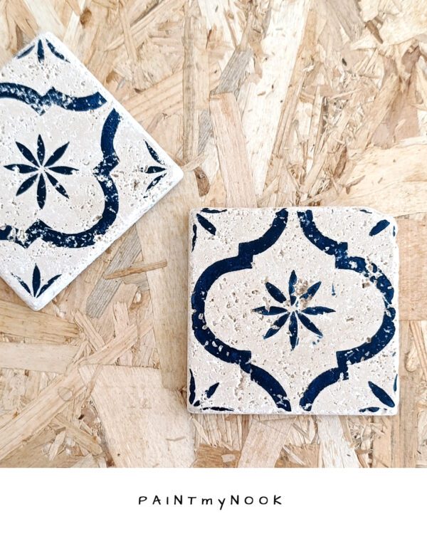 A travertine tile coaster with a deep blue linocut print on