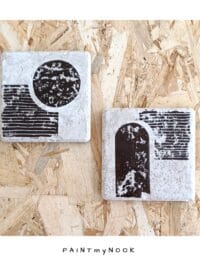 A pair of travertine tiles with a bauhaus style lino print on in a brown bistre color