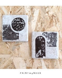 A pair of travertine tiles with a bauhaus style lino print on in a brown bistre color