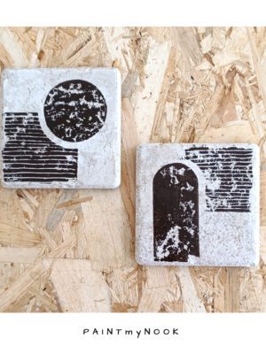 A pair of travertine tiles with a bauhaus style lino print on in a brown bistre color