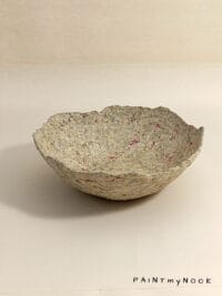 A beige papier mache bowl with pink details