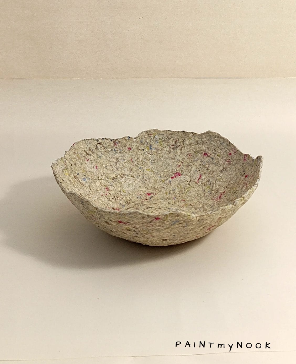 A beige papier mache bowl with pink details