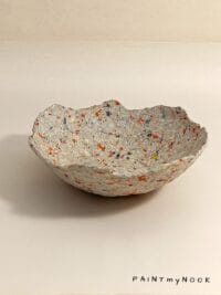 A beige papier mache bowl with orange details