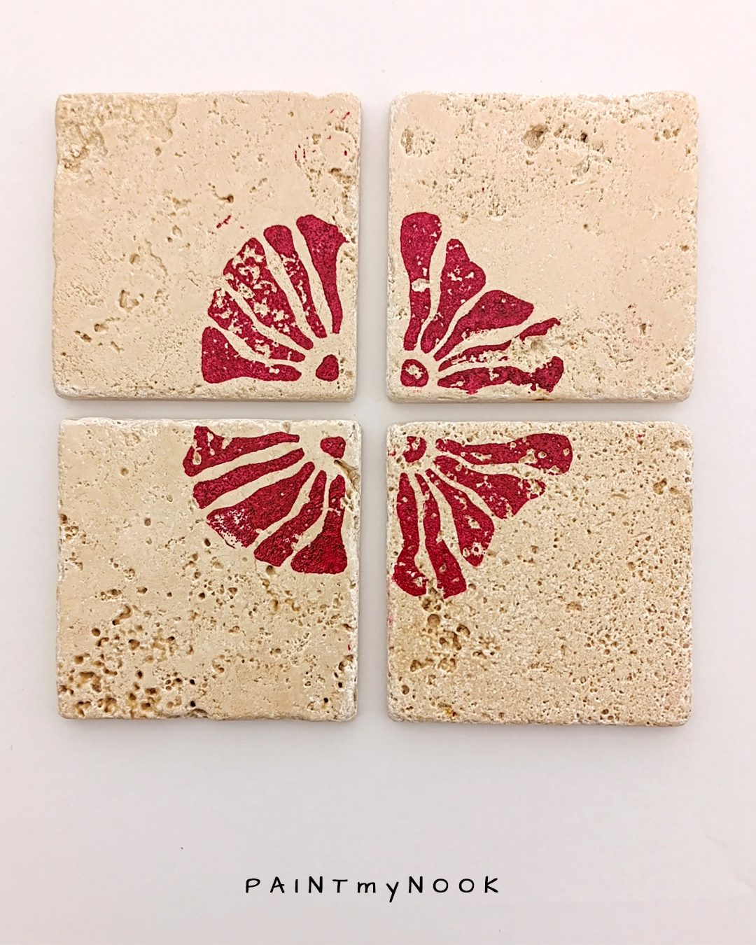 Four travertine coasters with a red flower print