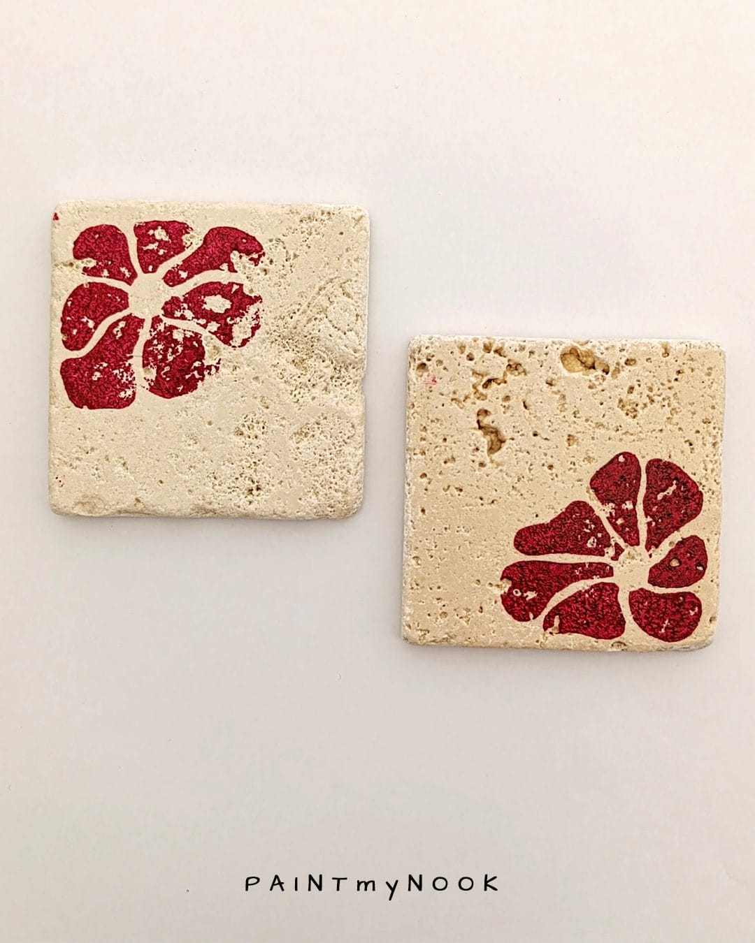 Two travertine coasters with a red flower print