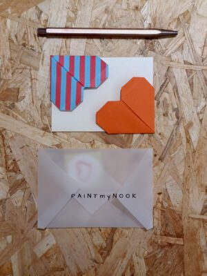 A pair of colorful origami heart bookmarks, a blank card, an envelope and a heart sticker