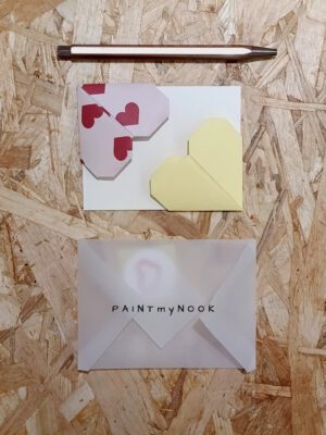 A pair of colorful origami heart bookmarks, a blank card, an envelope and a heart sticker
