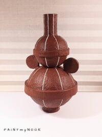 A papier mache vase with bold geometric forms in maroon red color with white stripes
