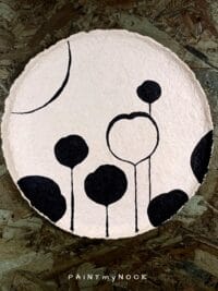 A beige papier mache plate with a black floral pattern