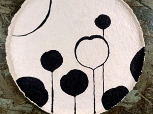 A beige papier mache plate with a black floral pattern