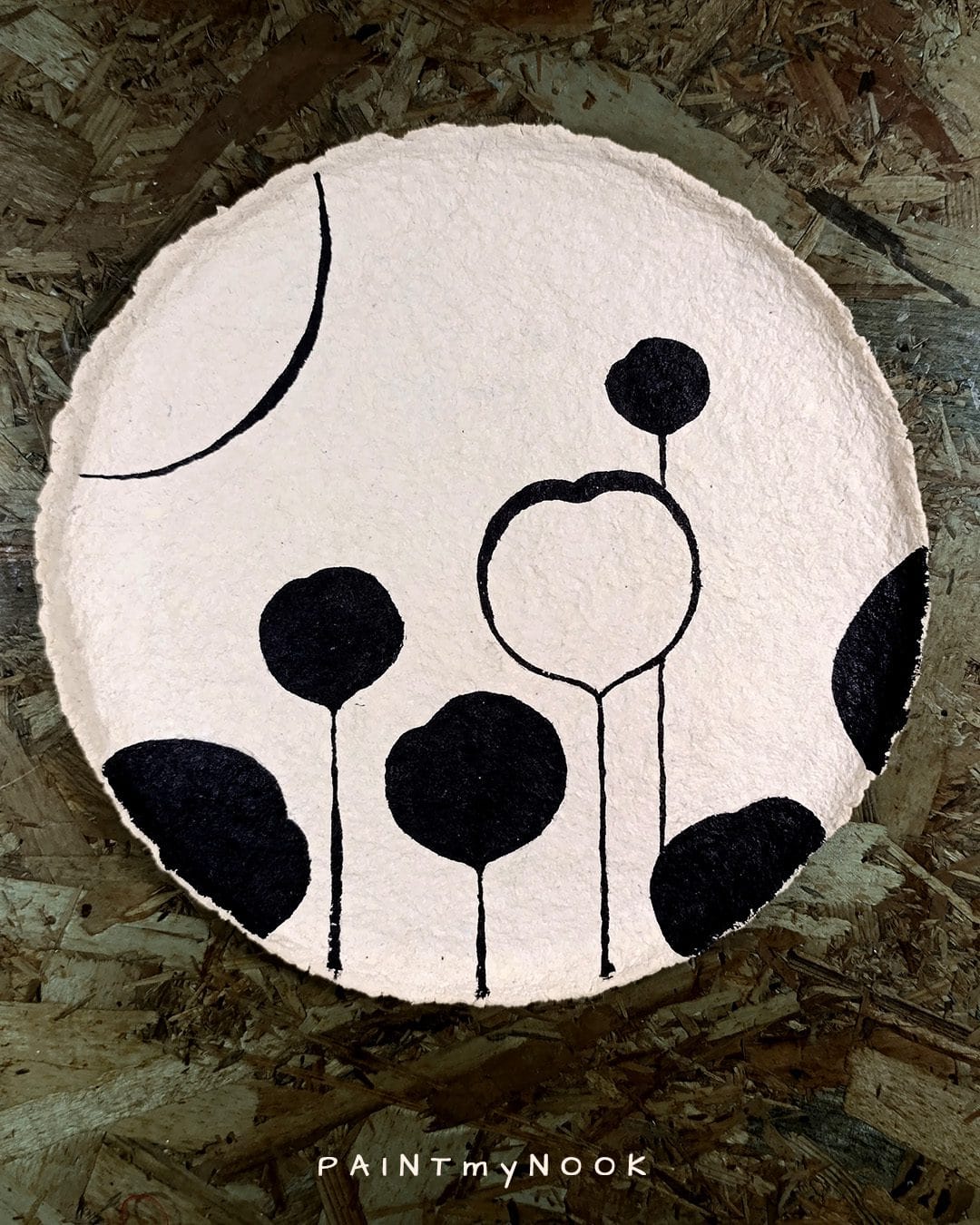 A beige papier mache plate with a black floral pattern