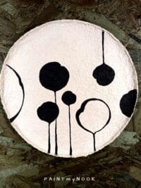 A beige papier mache plate with a black floral pattern