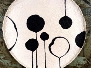 A beige papier mache plate with a black floral pattern
