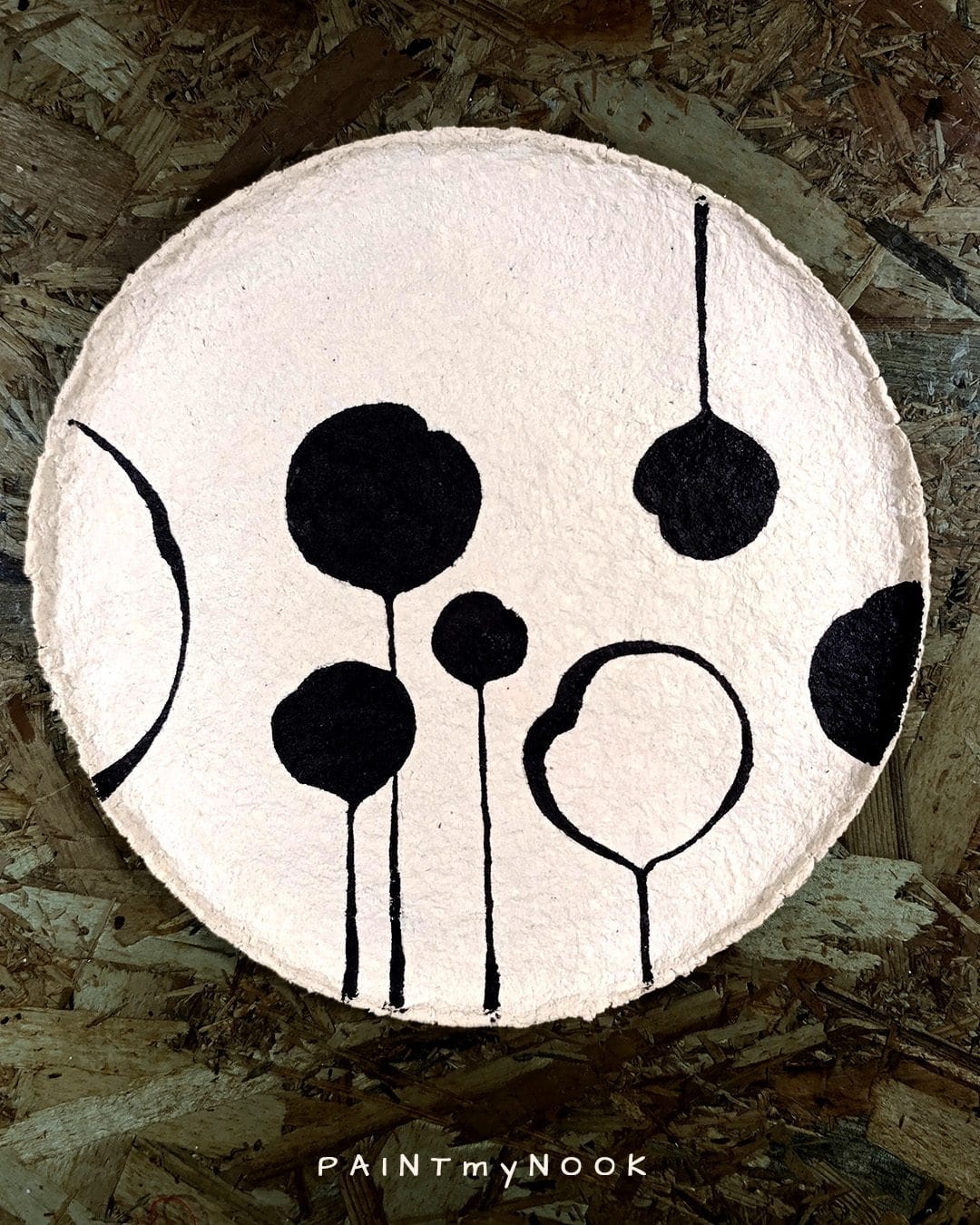 A beige papier mache plate with a black floral pattern